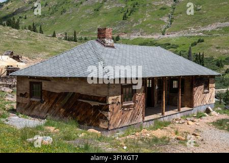 Abandoned wooden mining cabin stands below forested slopes at Animas Forks ghost town in Colorado, USA Stock Photo