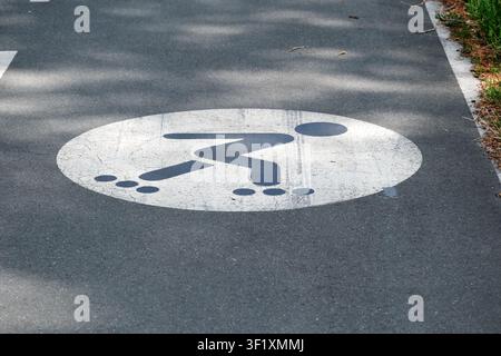 Close-up of a roller skating lane symbol painted on smooth asphalt pavement, marking a designated route for inline skating in a recreational park or o Stock Photo