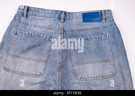 Light blue denim jeans back view, showcasing rear pockets and waistband, classic design elements, minimalistic environment, light blue shades, orange Stock Photo