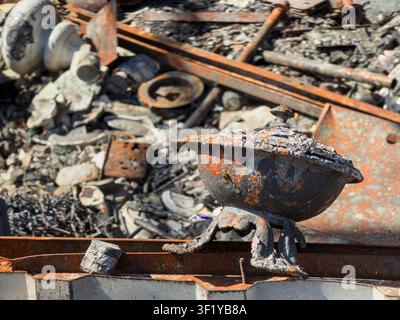 Rusted metal bowl with lid, scattered industrial parts, dark metal surface, weathered texture, natural sunlight, orange rust, brown tones, gritty indu Stock Photo