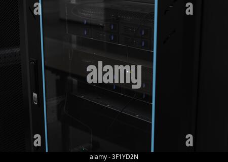 Glass-doored server rack housing rack servers and cabling. Dimly lit IT equipment conveys technology, connectivity, security and professional network Stock Photo