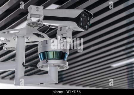 Ceiling-mounted surveillance setup featuring a security camera, CCTV unit and lidar sensor in a modern interior. Ideal concept image for monitoring, s Stock Photo