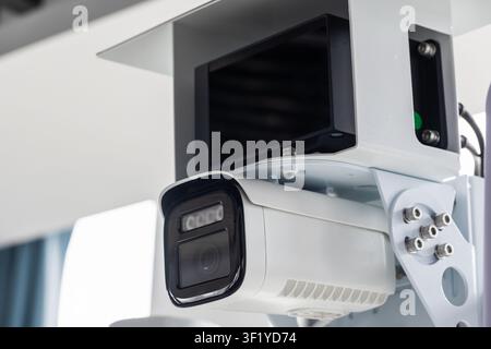 Close-up of a white security camera mounted indoors, highlighting CCTV surveillance technology and monitoring equipment used for building security, sa Stock Photo