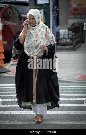 A devout Muslim woman wearing a stylish hijab and talking on her cell phone. In Jackson Heights, a Queens neighborhood called Little Bangladesh. Stock Photo