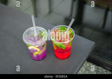 Bright homemade fruit lemonades with citrus slices, mint and ice served in takeaway cups. Refreshing summer drinks. Stock Photo