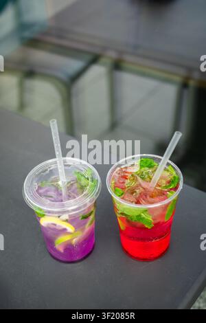 Refreshing fruit lemonades with fresh mint, citrus slices and ice in transparent plastic cups. Summer beverage concept. Stock Photo
