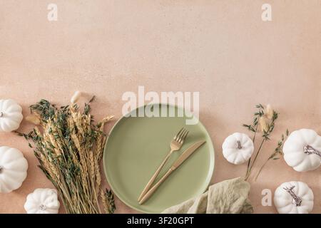 Minimal fall tablescape with ceramic plate, golden cutlery, white pumpkins and dried wheat. Cozy Thanksgiving or harvest dinner concept with large cop Stock Photo