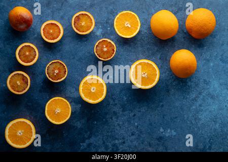 Freshly cut blood and navel oranges creating a healthy food pattern on a dark blue surface Stock Photo