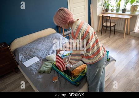 Woman traveler finishing packing personal belongings in suitcase for planned vacation journey. Stock Photo