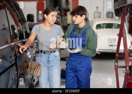 Guy mechanic consulting woman client on car door Stock Photo