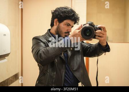 Professional photographer taking photos with camera indoors. Young photographer taking a mirror selfie with a professional camera Stock Photo
