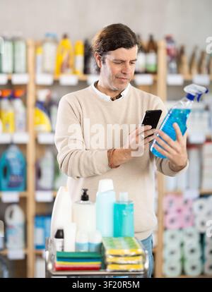 Middle-aged man scanning spray barcode in store Stock Photo
