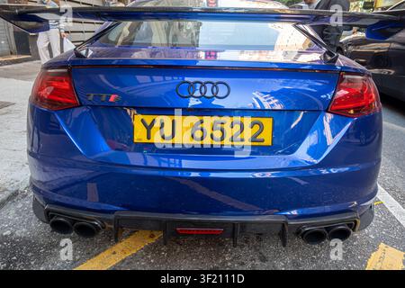 blue Audi TTS, a variant of the TT model featuring a prominent aftermarket GT-style wing spoiler, Hong Kong yellow vehicle registration plate Stock Photo