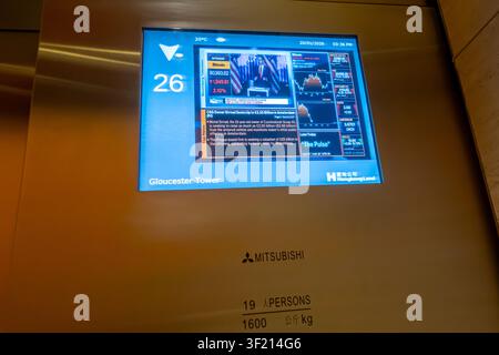 Mitsubishi Electric elevator interior, a cab, a digital display showing building information for Gloucester Tower and stock market data, Hong Kong Stock Photo