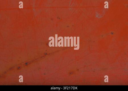 Detailed view of a distressed orange painted metal surface exhibiting visible scratches and aged imperfections creating an industrial backdrop scratch Stock Photo