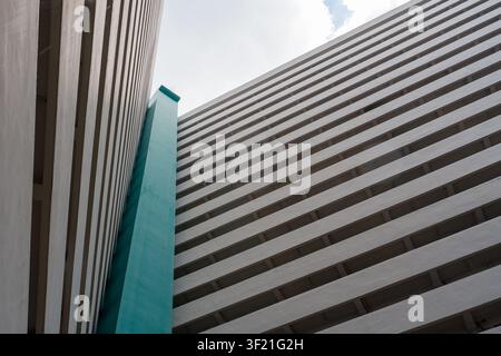 Modern building features bold geometric lines. White and teal stripes create striking architectural contrast. Low angle shot emphasizes structure's im Stock Photo
