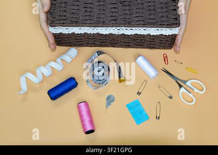 Flat Lay of Sewing Supplies with Wicker Storage Basket and Hands Stock Photo