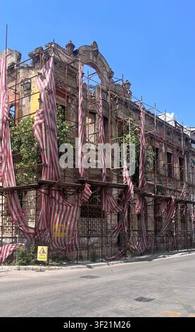 View of a historic building undergoing restoration with scaffolding and protective red-and-white striped fabric in Mostar, Federation of Bosnia, Bosni Stock Photo