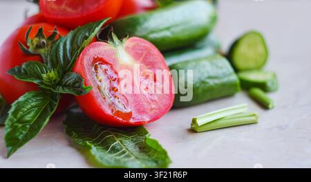 Tomatoes and cucumbers with greens on a white background Stock Photo