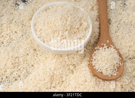 Grated coconut powder in bowl and wood spoon. Dry coco flakes pile, shredded desiccated coconut, tropical fruit chips texture, shaved nut Stock Photo
