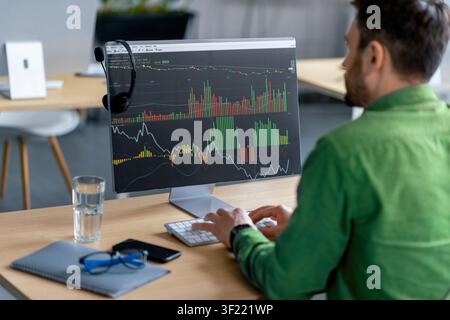 Focused Man Analyzing Stock Market Data On Computer Screen In Modern Office, Business Concept Stock Photo