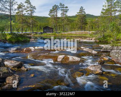A peaceful view across Svangtjern Lake near the small village of Bromma in Nesbyen Municipality, Buskerud, Norway. A traditional weathered wooden cabi Stock Photo