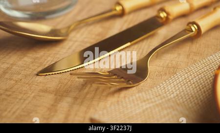 Golden cutlery set arranged on a wooden table Stock Photo