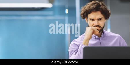 Man Focused on Computer Screen While Working in Office During Daytime Hours Stock Photo