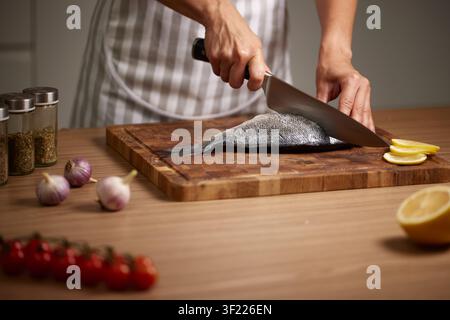 Chef slicing fresh sea bream fish on cutting board Stock Photo