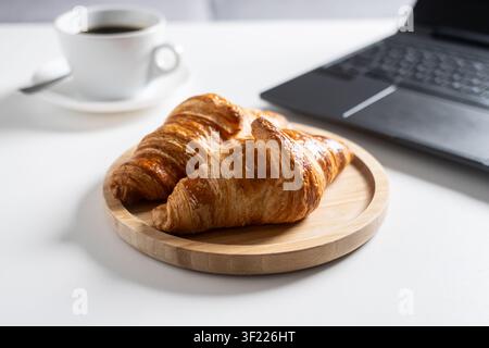 Breakfast with Coffee and Croissants on Home Office Desk. Stock Photo