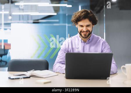 Man Using Laptop in Modern Office Setting During Work Hours Stock Photo