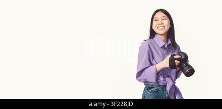 Smiling Asian Female Photographer Holding Camera In Studio, Happy Expression, Creative Concept Stock Photo