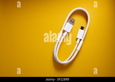 Close-up of a coiled USB-C to USB-A cable from a mobile phone on a orange surface. These cables are used for fast data transfer and charging of electr Stock Photo