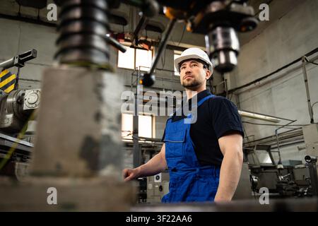 Industrial engineer standing beside CNC machine in modern manufacturing workshop Stock Photo