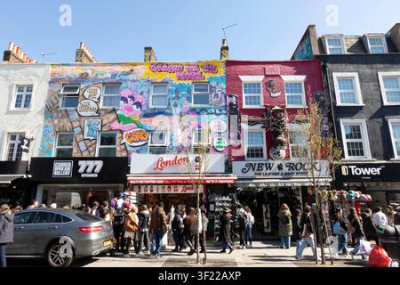 People walking past colorful retail shopfronts with vibrant street art murals along Camden High Street in London, England, United Kingdom. Stock Photo