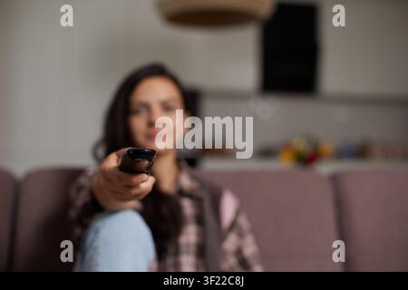 Woman holding remote control changing television channel Stock Photo
