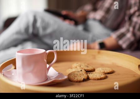Person relaxing with coffee and cookies on tray Stock Photo