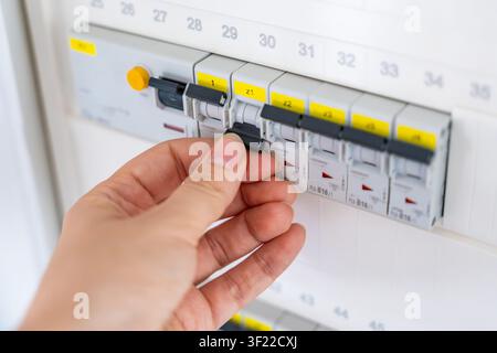 Hand switching an electrical circuit breaker in a residential distribution panel. Electrical safety and power control support maintenance, energy Stock Photo