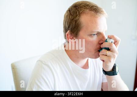 Man inhaling medication using an asthma inhaler for breathing and respiratory health Stock Photo