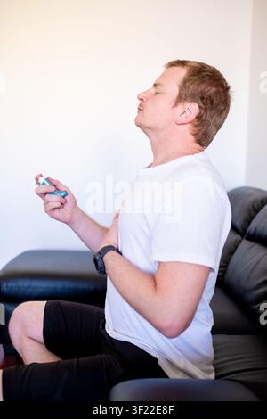 Man struggling to breathe using an inhaler for respiratory health treatment Stock Photo