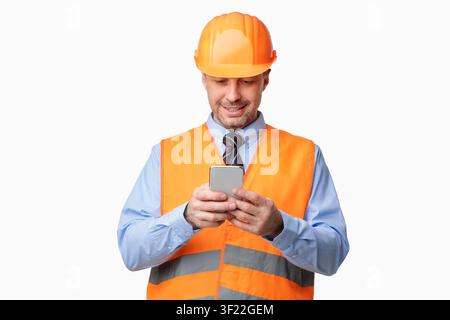 Construction Worker Using Smartphone Standing On White Studio Background Stock Photo