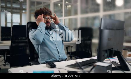 Tired exhausted Arabian ethnic business man working with computer sad suffering with headache problem painful hurt upset stressed businessman work Stock Photo