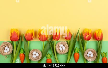 Easter composition with beautiful red and yellow tulips flowers and Easter eggs in nest. Top view, flat lay with copy space. Stock Photo