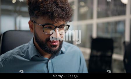 Concentrated smiling Arabian ethnic business man using computer looking at screen desktop monitor smile ethnicity businessman in glasses working enjoy Stock Photo