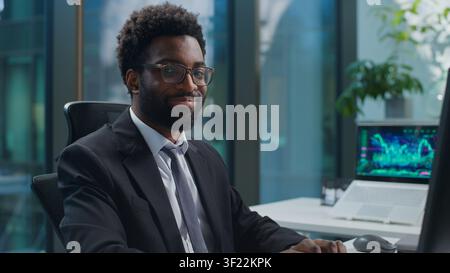 African American business man working typing computer keyboard smiling happy cheerful looking at camera at office table. Ethnic businessman male Stock Photo