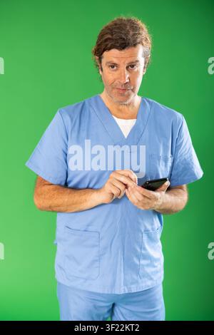 Adult male medic scrolling smartphone on green screen Stock Photo