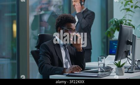 Busy multiethnic coworkers African American Caucasian men talking mobile phone cellphone multitask professional employees businessmen males business Stock Photo