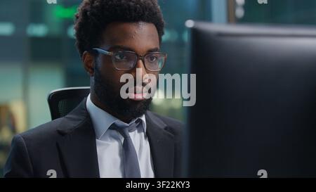 Concentrated African American business man entrepreneur leader working with computer at table. Serious businessman male expert employee work browsing Stock Photo