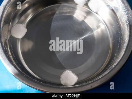 Ice cubes floating in stainless steel dog water bowl Stock Photo