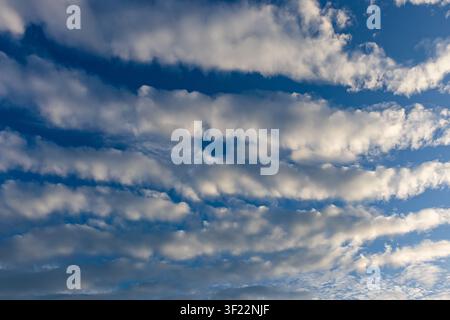 Cloud bands stretching across vivid blue sky in diagonal formation Stock Photo